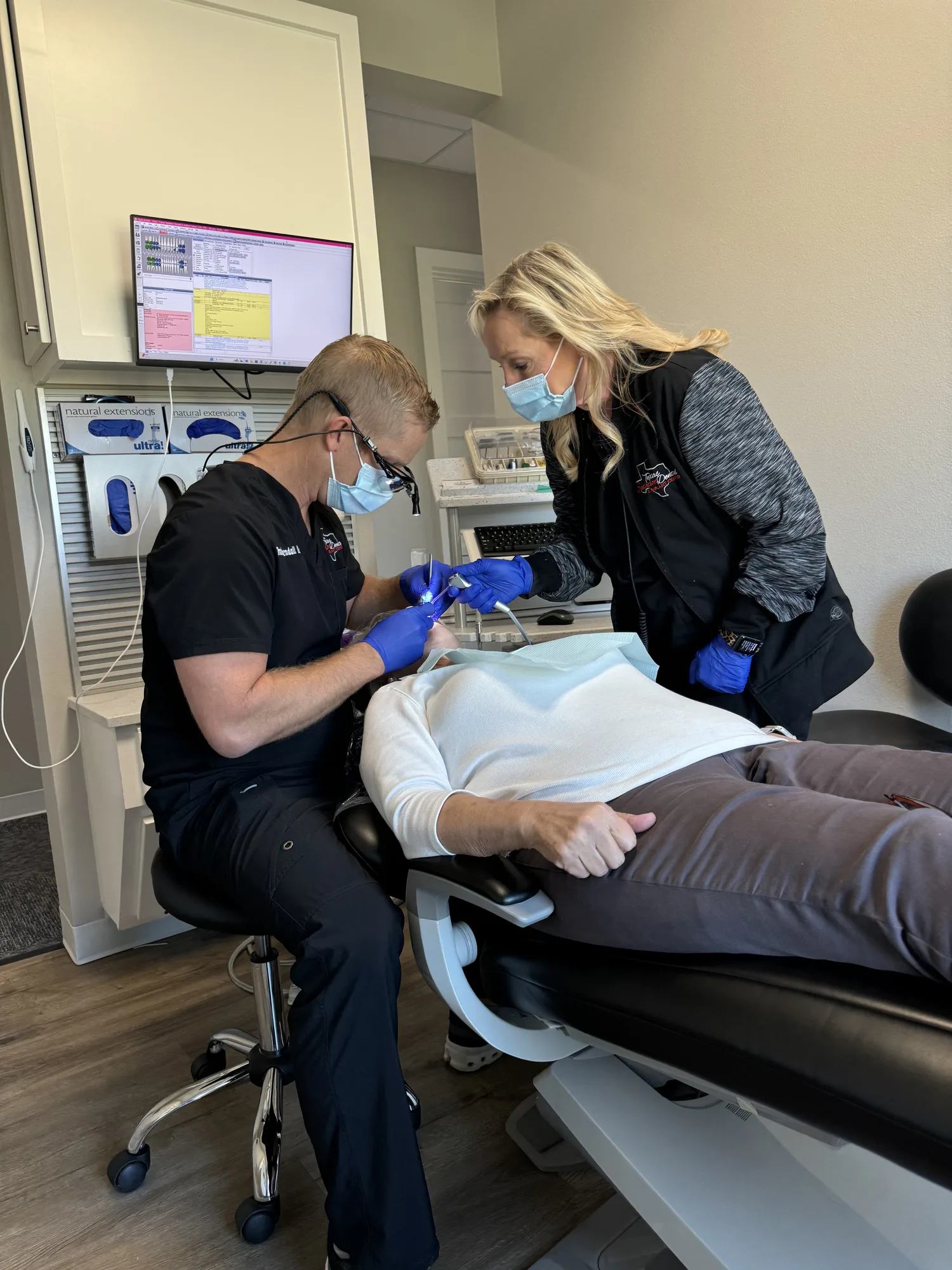 Dentist and assistant working together on a reclined patient during a dental procedure