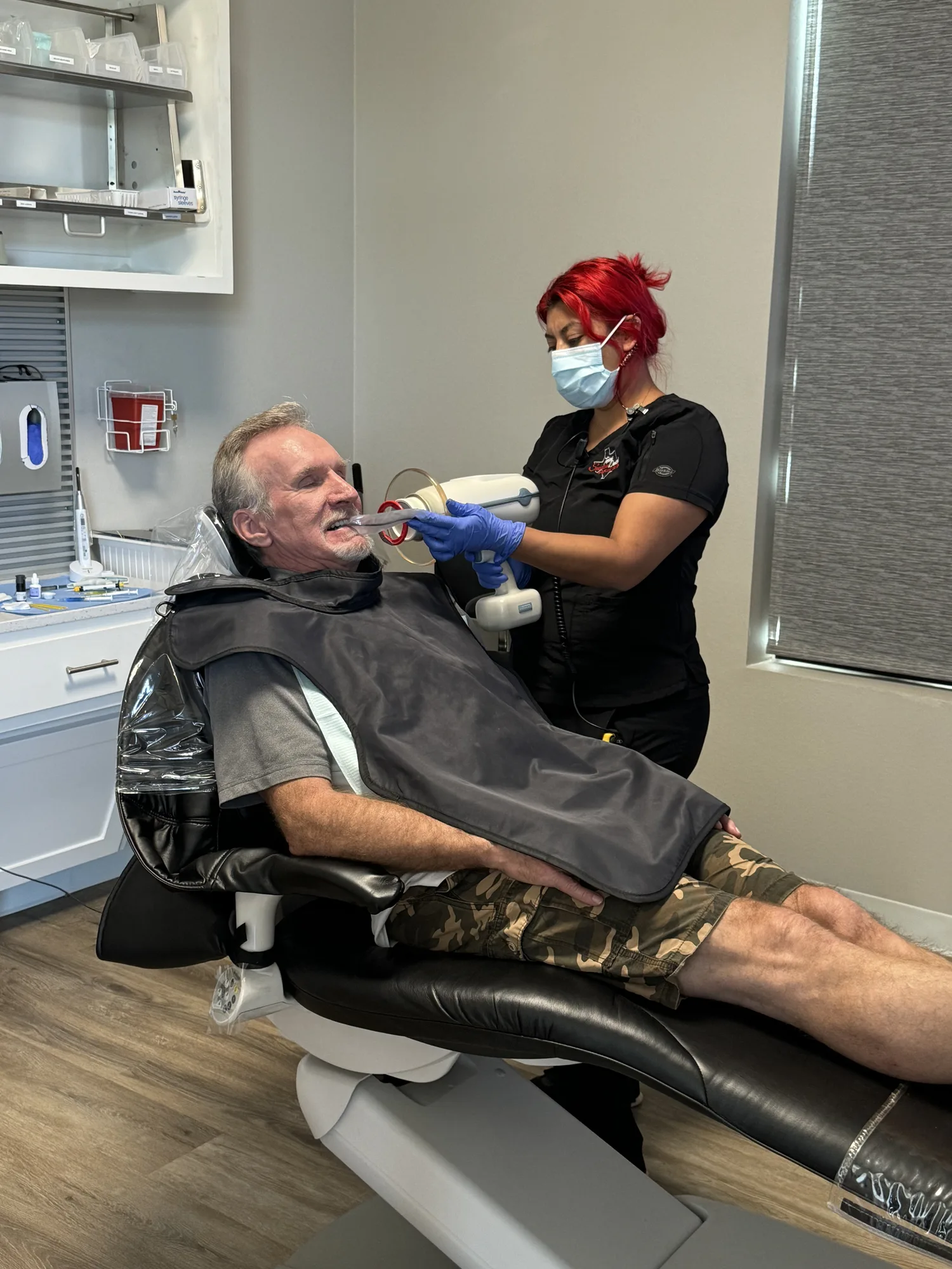 Patient reclined comfortably in the dental chair during treatment with a team member assisting nearby